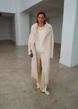 Pantalón de tiro medio confeccionado en tejido satinado de corte recto y largo, con bolsillos laterales, aberturas en el bajo y detalle de costuras.