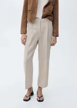 Pantalón de lino color beige, de tiro alto y diseño recto con bajo cropped, con pinzas delanteras, trabillas para cinturón y cierre frontal con cremallera y botón.