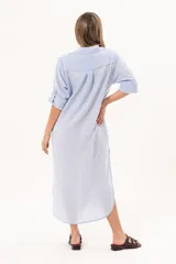 Vestido camisero largo color celeste, de silueta relajada con abotonadura frontal completa, cuello camisero y mangas regulables. Presenta tajos laterales y detalle de bordado sutil en la manga.