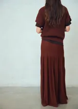 Falda larga de punto color marrón chocolate, con diseño evasé, tiro medio, cintura elástica y detalle de costuras verticales.