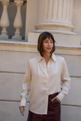 Camisa de manga larga color negro con apliques de strass plateados distribuidos en todo el diseño. Presenta cuello clásico, cierre frontal con botones y puños abotonados.