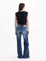 Jeans de denim azul con diseño clásico de cinco bolsillos, silueta semi oxford de tiro medio-alto, entallada en caderas y muslos con botamanga acampanada. Presenta lavado en azul medio con contrastes y desgastes focalizados.