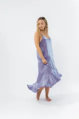 Vestido midi color lila metálico de breteles finos regulables, escote en V y ruedo asimétrico con leve vuelo.