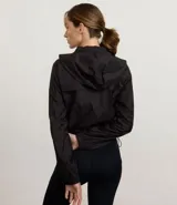 Campera cortavientos deportiva de corte cropped, color verde oscuro. Presenta capucha, cierre frontal con cremallera, mangas largas con puños elásticos y cordón ajustable en el ruedo.