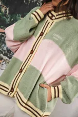 Cardigan oversized de punto grueso, color azul marino y blanco con franjas rojas y rosadas en el cuello, puños y solapa. Tiene botones grandes marrones y el logo de Anthea bordado en el pecho.