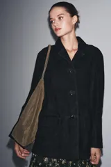 Chaqueta de ante negra con cuello solapa de muescas y manga larga. Tiene bolsillos con solapa en delantero y cierre frontal con botones.