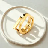 Anillo dorado de acero quirúrgico con baño de oro 18k, de diseño arquitectónico moderno con forma geométrica.