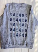 Buzo gris de corte clásico con estampado de hojas azules en la espalda.