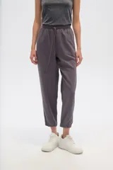 Pantalon de corte relajado, color gris, con cintura elástica y cordón ajustable. Presenta bolsillos frontales tipo parche y puños elásticos en los tobillos.