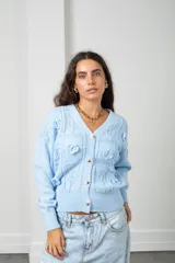 Saco de punto color celeste con cuello en V, cierre frontal con botones y apliques de flores bordadas en relieve. Presenta un diseño de tejido con texturas y mangas largas.