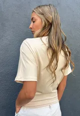 Blusa color cruda de manga corta, con cuello drapeado y diseño holgado.