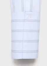 Camisa de corte recto con diseño de rayas verticales en tonos celestes y blancos. Presenta cuello camisero con solapas amplias, cierre frontal de botones ocultos bajo tapeta y mangas largas con puños abotonados.