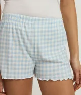 Conjunto de pijama compuesto por musculosa lisa con botones y short de cuadros vichy con cintura elástica y ruedo con volados.