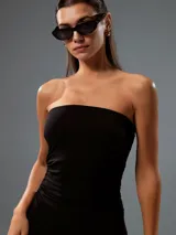 Vestido corto negro strapless, de corte ajustado en el torso con fruncidos laterales y falda levemente evasé.