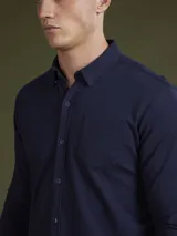 Camisa de hombre color azul marino, de piqué con cuello abotonado y manga larga.