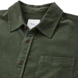 Camisa verde de pana de manga larga con cuello clásico, cierre con botones y bolsillo en el pecho.