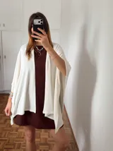 Ruana de tejido fino en color blanco, con diseño abierto y caída fluida, ideal para capas ligeras.