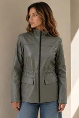 Campera estilo cazadora color verde militar de cuero ovino italiano, con cuello mao, cierre frontal, bolsillos frontales con solapa y cordón interno ajustable en la cintura.