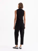 Pantalón tipo babucha de color negro, con cintura elástica y cordón de ajuste, bolsillos laterales y costuras verticales decorativas en el frente.