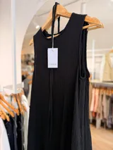 Vestido largo negro sin mangas, confeccionado en tela texturada con relieve, de corte fluido y diseño versátil.