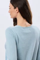 Buzo tejido de algodón color beige, de manga larga, con cuello redondo y delicados motivos bordados distribuidos en la prenda.