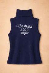 Chaleco de tejido de punto color crema con cuello alto y bordado frontal en color bordó con la inscripción Vdamiani 2009. Presenta detalles de volados en las sisas.