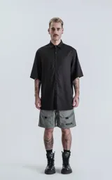 Camisa de manga corta color negro, con cuello clásico y cierre frontal de botones.