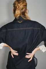 Camisa de jean de corte entallado con cierre frontal de botones, cuello clásico y mangas largas con puños ajustables. Presenta un diseño versátil ideal para combinar con diversas prendas.