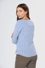 Remera de manga larga con cuello redondo, confeccionada en tejido suave con estampado de pequeñas hojas en tonos azul y rojo sobre fondo celeste.