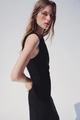 Vestido midi negro de cuello redondo y manga sisa, con detalle de drapeado en la cintura y cierre lateral con cremallera oculta.
