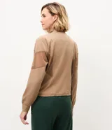 Campera deportiva rompevientos Get Over color bordó con cuello alto, cierre frontal y mangas largas. Cuenta con recortes de tul respirable en las mangas y cintura ajustable.