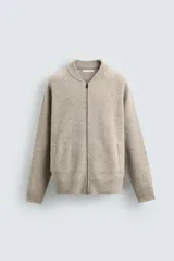 Chaqueta tipo bomber de punto en hilatura de lana, con cuello subido, manga larga, bolsillos de vivo en la cadera, acabados en rib y cierre frontal de cremallera.