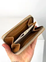Mini billetera de cuero con textura efecto cocodrilo y cierre perimetral. Presenta un parche central con el logo de la marca grabado.