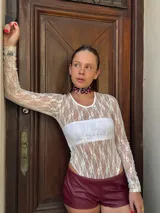 Body de encaje blanco con mangas largas y cuello redondo.