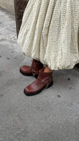 Bota corta de cuero color marrón con punta cuadrada, suela track negra y estribo desmontable con hebilla metálica.