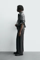 Pantalón de corte balloon fit, color negro, con bolsillos laterales de vivo y bolsillos traseros con solapa. Presenta cierre frontal con cremallera y botón.