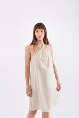 Vestido corto color beige, con escote halter y corte suelto.