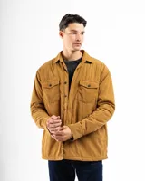 Sobre camisa de pana color marrón, con cierre frontal de botones, cuello clásico y dos bolsillos frontales con solapa y botón.