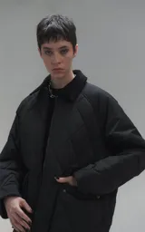 Campera oversize de microfibra opaca con diseño matelaseado de rombos. Presenta cuello de corderoy a tono, cierre frontal metálico y dos amplios bolsillos delanteros con solapa y broche snap. Interior forrado y relleno con guata térmica.
