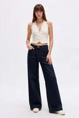 Pantalón jean azul oscuro de corte ancho, tiro medio, con bolsillos delanteros aplicados y costuras pespunteadas en contraste.