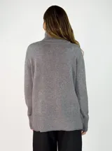 Sweater de punto gris con cuello alto, manga larga con puños acanalados y diseño holgado con costura central vertical.