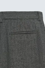 Pantalón de traje relaxed fit en color gris oscuro con diseño de espiga. Cuenta con bolsillos frontales, bolsillos traseros de vivo y cierre frontal con cremallera y botón.