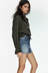 Falda corta de denim con tiro medio, cierre frontal con botones metálicos y bajo con acabado deshilachado.