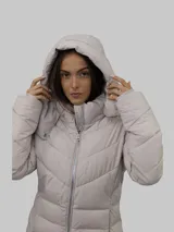 Campera puffer color beige con cierre frontal y bolsillos laterales con cierre. Tiene capucha desmontable y relleno acolchado.