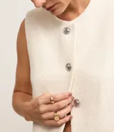 Chaleco blanco de tweed con cuello redondo, abotonado en el frente y corte entallado.