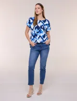 Blusa de silueta holgada y recta, confeccionada en crepe de poliéster con estampado animal print. Presenta escote redondo clásico, mangas cortas de hombro caído con puño doblado y ruedo ligeramente curvo.