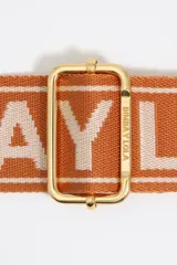 Correa bandolera ajustable de tejido negro con el logo de Bimba y Lola en jacquard. Tiene detalles en piel vacuna negra y herrajes metálicos dorados.