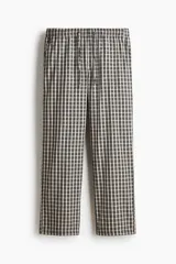 Pantalón de corte relajado confeccionado en popelina de algodón con estampado de cuadros. Presenta cintura elástica con cordón de ajuste y bolsillos laterales.