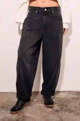 Jean de corte baggy con diseño barrel, tiro medio y acabado en color negro lavado. Presenta cierre frontal con botón y bolsillos laterales y traseros.