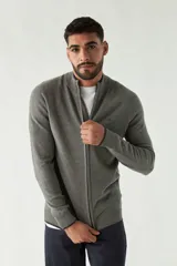 Campera tejida gris con cuello alto, cierre frontal con cremallera, puños y logo bordado en el pecho.